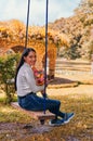 Woman sitting on a swing holding a bouquet of flowers while looking at camera Royalty Free Stock Photo