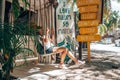 Woman sitting on swing seat of coconut shop with drink menu at roadside