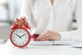 Woman sitting at table with book and clicking on alarm clock closeup Royalty Free Stock Photo