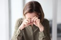 A woman sitting at a table in the office wipes her eyes