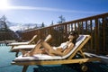 Woman sitting on a terrace in bikini in the snowy mountains