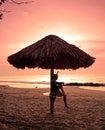 Woman sitting under a parasol on the beach.
