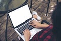 A woman sitting , using and typing on laptop with blank white screen on thigh at outdoor background Royalty Free Stock Photo