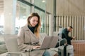 Woman sitting in waiting room with laptop near valise. Royalty Free Stock Photo