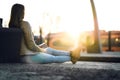 Woman sitting and waiting for train at station at sunset. Royalty Free Stock Photo