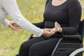 Woman sitting in a wheelchair being helped attain a meditation pose by another woman