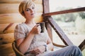 Woman sitting in a wicker chair on a balcony with a cup of tea