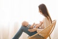 Woman sitting in wicker chair with newborn baby on lap Royalty Free Stock Photo