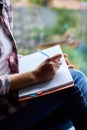 Woman, sitting at window at home, writes in notebook goals Royalty Free Stock Photo