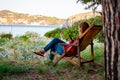 Woman sitting on wooden deckchair with smart phone on the beach in Village Camping Odyssey located in Cilento National