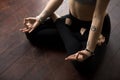 Woman sitting on wooden floor in Lotus pose, making mudra