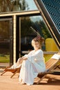 Woman sitting on wooden folding chair on terrace of a-frame cabin