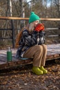 Middle-aged woman enjoying hot tea drinking while resting after hiking on wooden pathway in forest