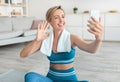 Woman sitting on yoga mat using smartphone waving hand Royalty Free Stock Photo