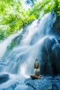 Woman sitting yoga pose in spiritual relaxation serenity and meditation at stunning beautiful waterfall and rain forest in Bali Su Royalty Free Stock Photo