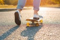 Woman skateboarding at sunrise. Legs on the skateboard, moves to