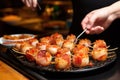 a woman skewering scallops with bacon