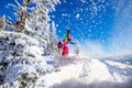 Woman skier jumping in pink skis on background of blue sky and snowy forest in mountains, dust from snow Royalty Free Stock Photo