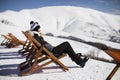 Woman skier relaxing in a lounge chair after skiing in the mountains in winter