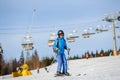 Woman skier skiing downhill at ski resort against ski-lift Royalty Free Stock Photo