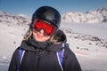 Woman skier on the slope of a mountain resort. Portrait of a young woman smiling in ski equipment, goggles and a helmet Royalty Free Stock Photo