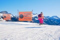 Woman skier starting a black ski run, reserved for experts only, passing two warning signs saying Difficult Slope in Italian