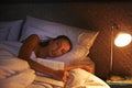 Woman, sleep and book in bed and light, dreaming female person or night lamp for story and novel. Relax, hobby and tired Royalty Free Stock Photo