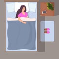 Woman sleeping in her bed, top view. Girl sleeps peacefully with smartphone near her head. Slippers on the Mat near the bed. Royalty Free Stock Photo