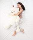 Woman sleeping with large teddy bear