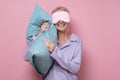 Woman in sleeping mask wearing pajama hugging bed pillow at night time with happy face smiling Royalty Free Stock Photo