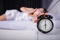 woman sleeping and wake up to turn off the alarm clock in morning Royalty Free Stock Photo