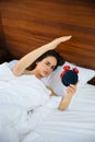 Woman sleeping and wake up to turn off the alarm clock in the morning. Royalty Free Stock Photo