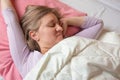 Woman sleeps on the back. Close-up portrait of 40 years woman with calm and relax face sleeping on pink pillow