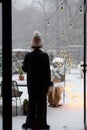 Woman in sleepwear and hat goes out on her snowy backyard