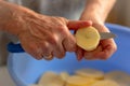 Fresh tasty potatoes cut into perfect round slices. Woman sliced potatoes in round shape with knife in a blue bowl