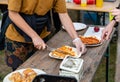 Woman slices a pizza that just came out of a outdoor bread oven.