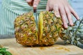 Woman slicing a fresh pineapple on a wooden cutting board Royalty Free Stock Photo