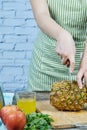 Woman slicing a fresh pineapple on a wooden cutting board Royalty Free Stock Photo