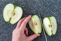 Woman slicing a green Granny Smith apple on a plastic man made faux gray granite cutting board, hands and chefs knife, apple halve Royalty Free Stock Photo