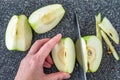 Woman slicing a green Granny Smith apple on a plastic man made faux gray granite cutting board, hands and chefs knife, apple quart Royalty Free Stock Photo