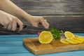 Woman slicing lemon on a wooden cutting board in the kitchen Royalty Free Stock Photo
