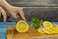 Woman slicing lemon on a wooden cutting board in the kitchen Royalty Free Stock Photo
