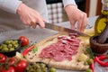 Woman slicing Spanish sausage fuet salami with knife on a domestic kitchen