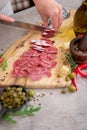 Woman slicing Spanish sausage fuet salami with knife on a domestic kitchen