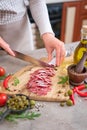 Woman slicing Spanish sausage fuet salami with knife on a domestic kitchen