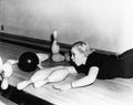 Woman sliding down bowling alley with ball Royalty Free Stock Photo