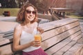 Woman with slim figure drinks freshly squeezed orange juice from a plastic cup. Useful and harmful beverages