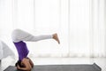 Woman slim, young teen sits on the asana in the yoga room calmly and relaxed. The light behind the window is light and
