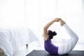 Woman slim, young teen sits on the asana in the yoga room calmly and relaxed. The light behind the window is light and