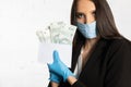 Businesswoman in a protective mask and protective gloves puts a bundle of paper banknotes into the envelope